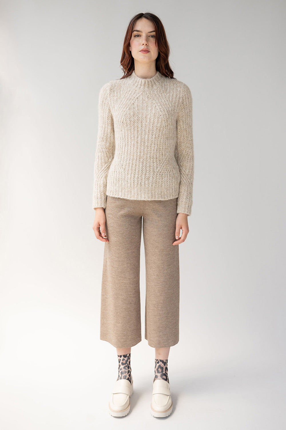 Head to toe cream outfit top is a ribbed sweater paired with wide leg trousers styled with white loafers