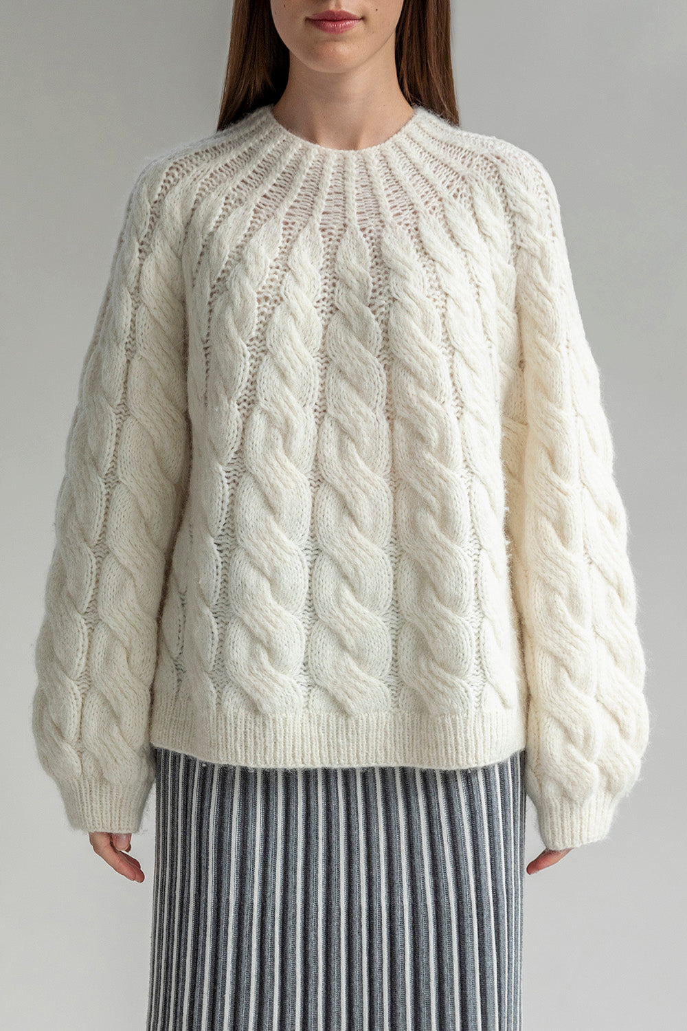 The Tomo Mix Cable Handknit in Ivory. The textured pullover is sustainably made by Peruvian artisans crafted from 70% baby alpaca 23% nylon and 7% merino wool.