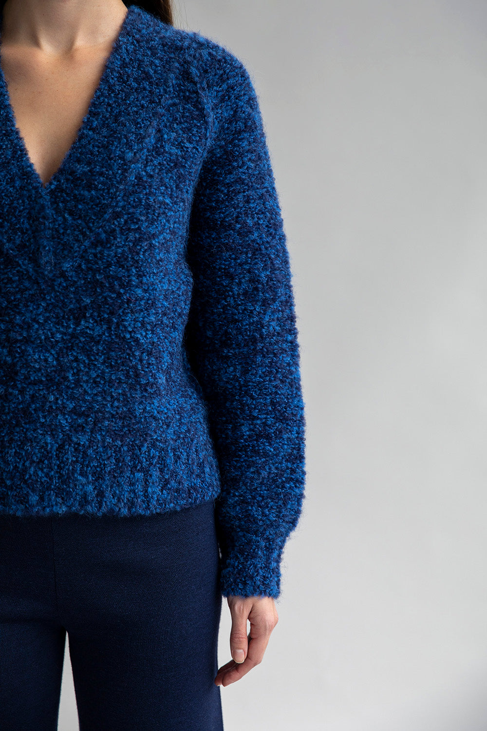 Detail shot of V Neck Bouclè Pullover showcasing its soft bouclè yarn texture with subtle contrast colors that create a beautiful marl effect.
