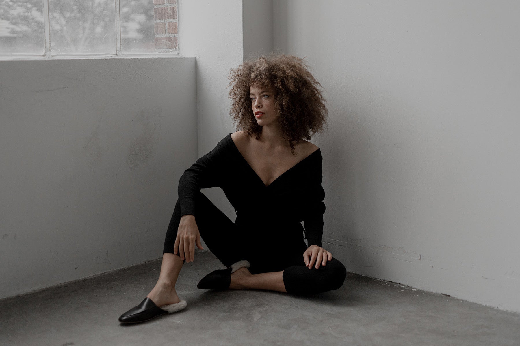 Model wears the T Neck Bodysuit in black sustainably made from baby alpaca and silk designed by SSKEIN