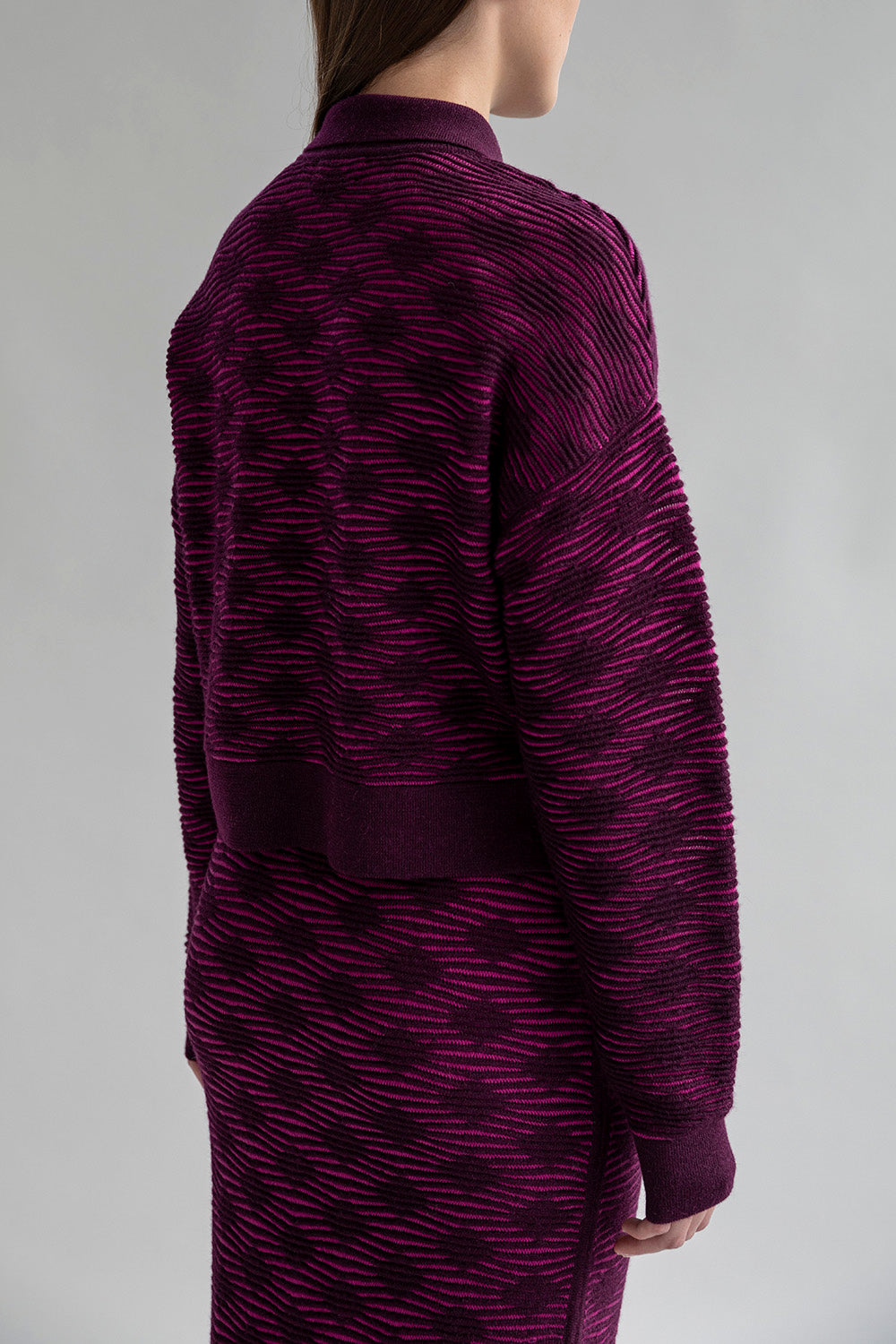 Back view of the Amelie Polo sweater  in aubergine, highlighting its relaxed silhouette. 