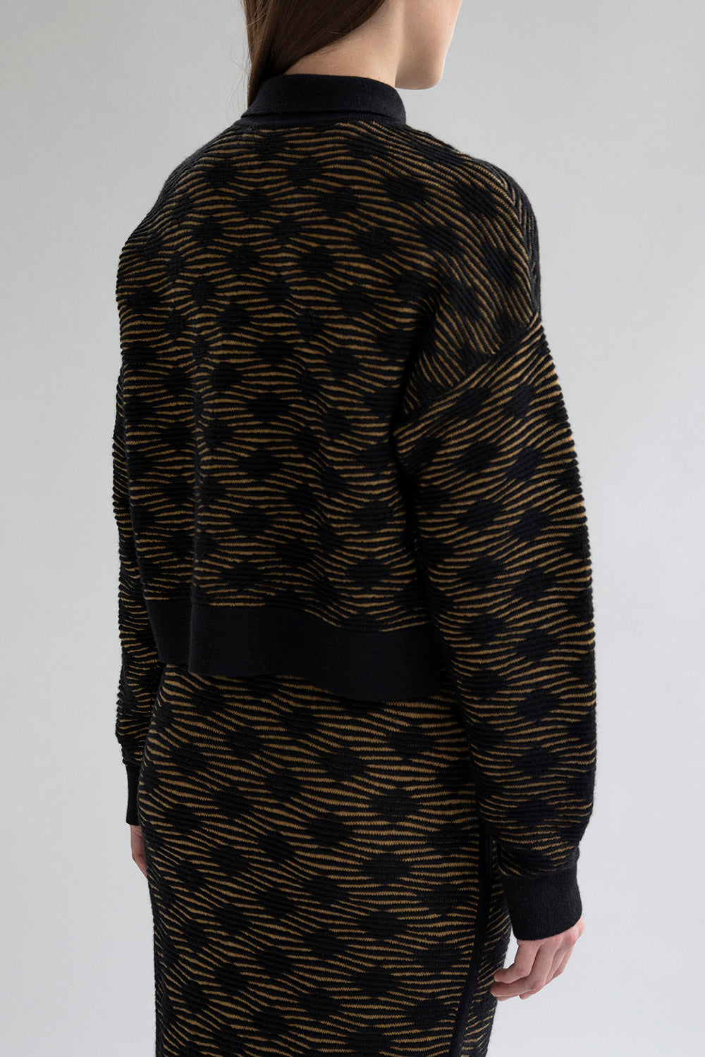 Back view of the Amelie Polo sweater  in golden black highlighting its relaxed silhouette. 