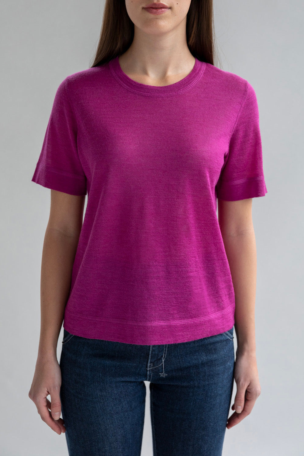 A woman wearing a short sleeve sweater tee in fuchsia made from baby alpaca silk.