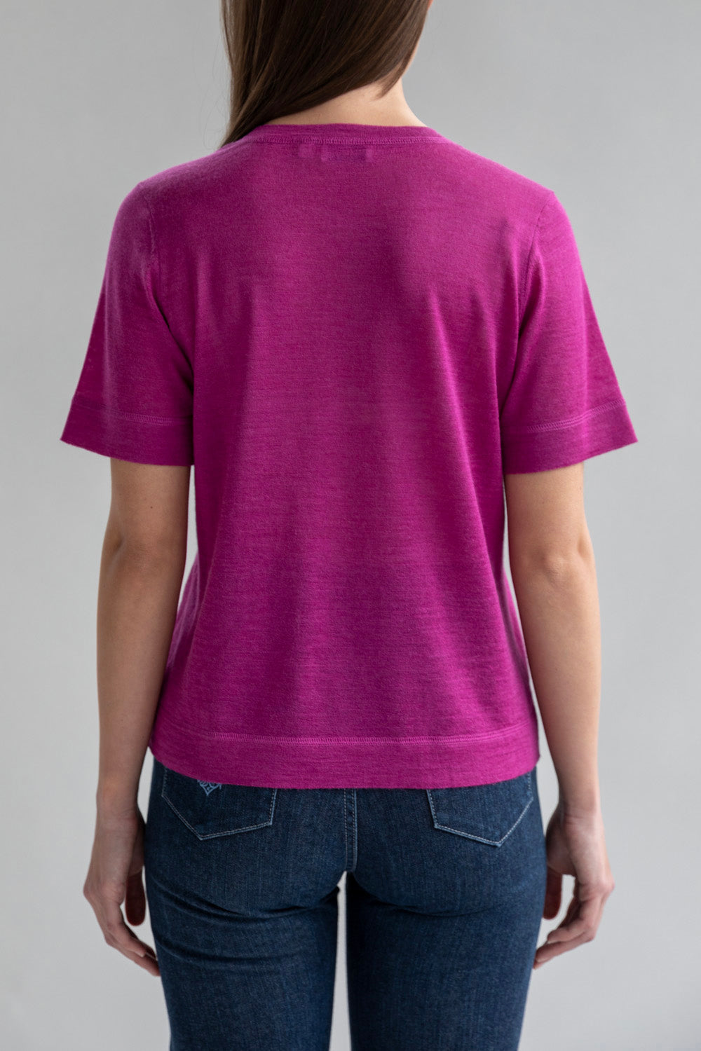 Full back view of a model in a relaxed fit fuchsia crew neck sweater tee.