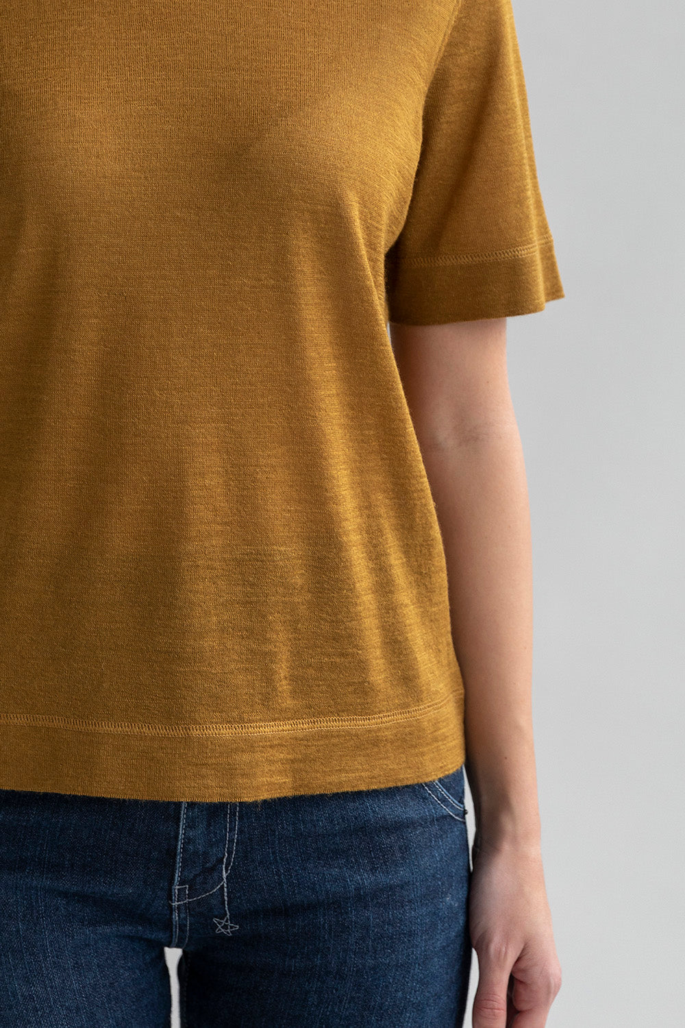 Close-up of self-yarn cover stitch details on the golden crew neck sweater tee.