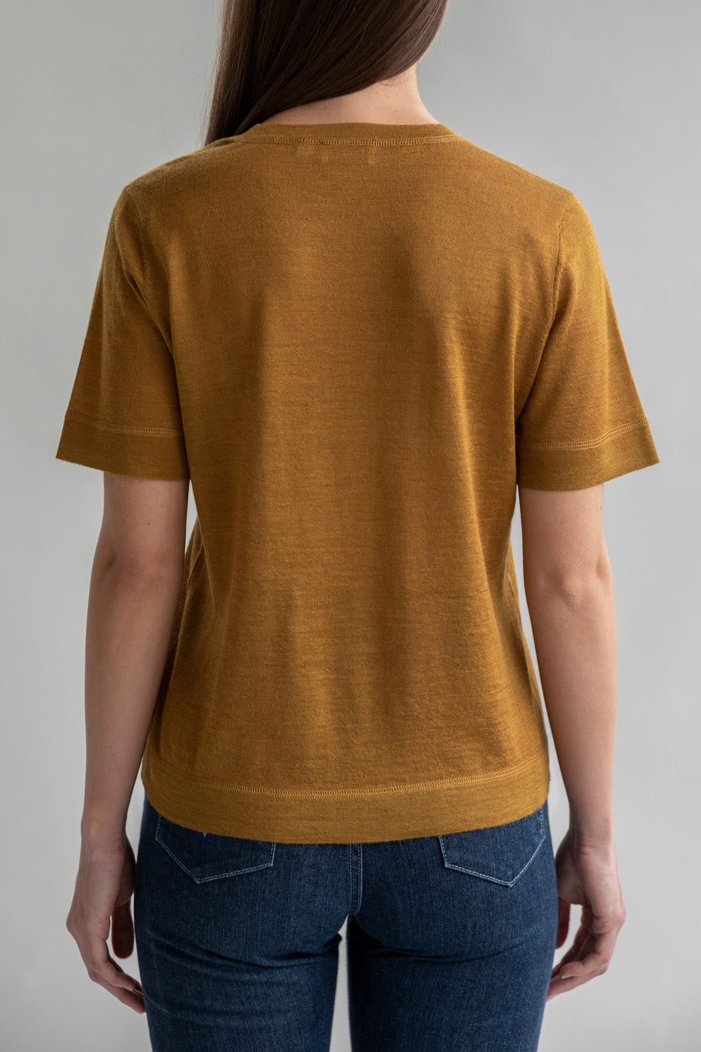 Full back view of a model in a classic relaxed fit golden sweater tee that hits at the high hip.