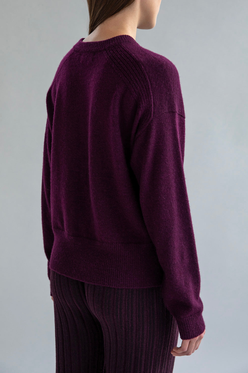 Back view of the crew neck boxy pullover in aubergine, highlighting it’s relaxed silhouette.