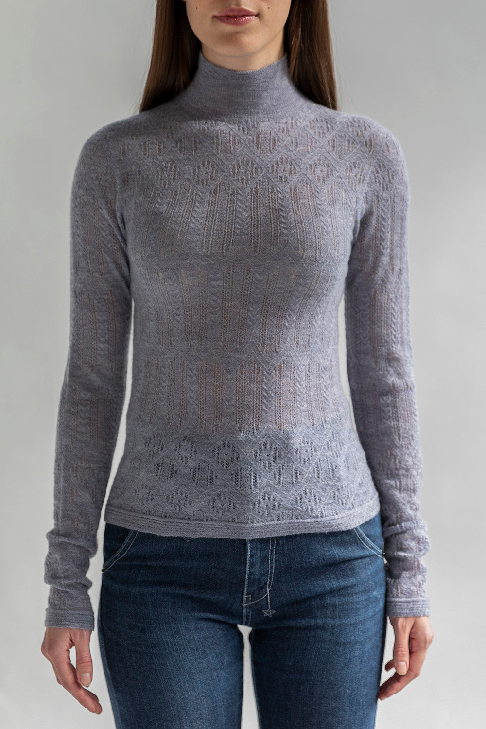 Woman wearing a slightly sheer grey lace pointelle turtleneck pullover, made from 100% cashmere.