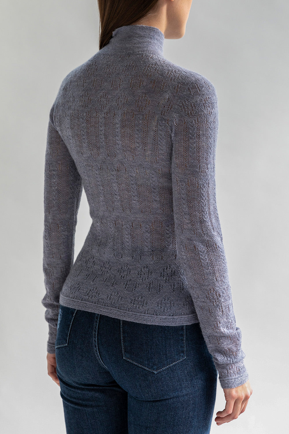 Back view of a woman wearing a lace pointelle pullover in grey showcasing a fitted silhouette. 