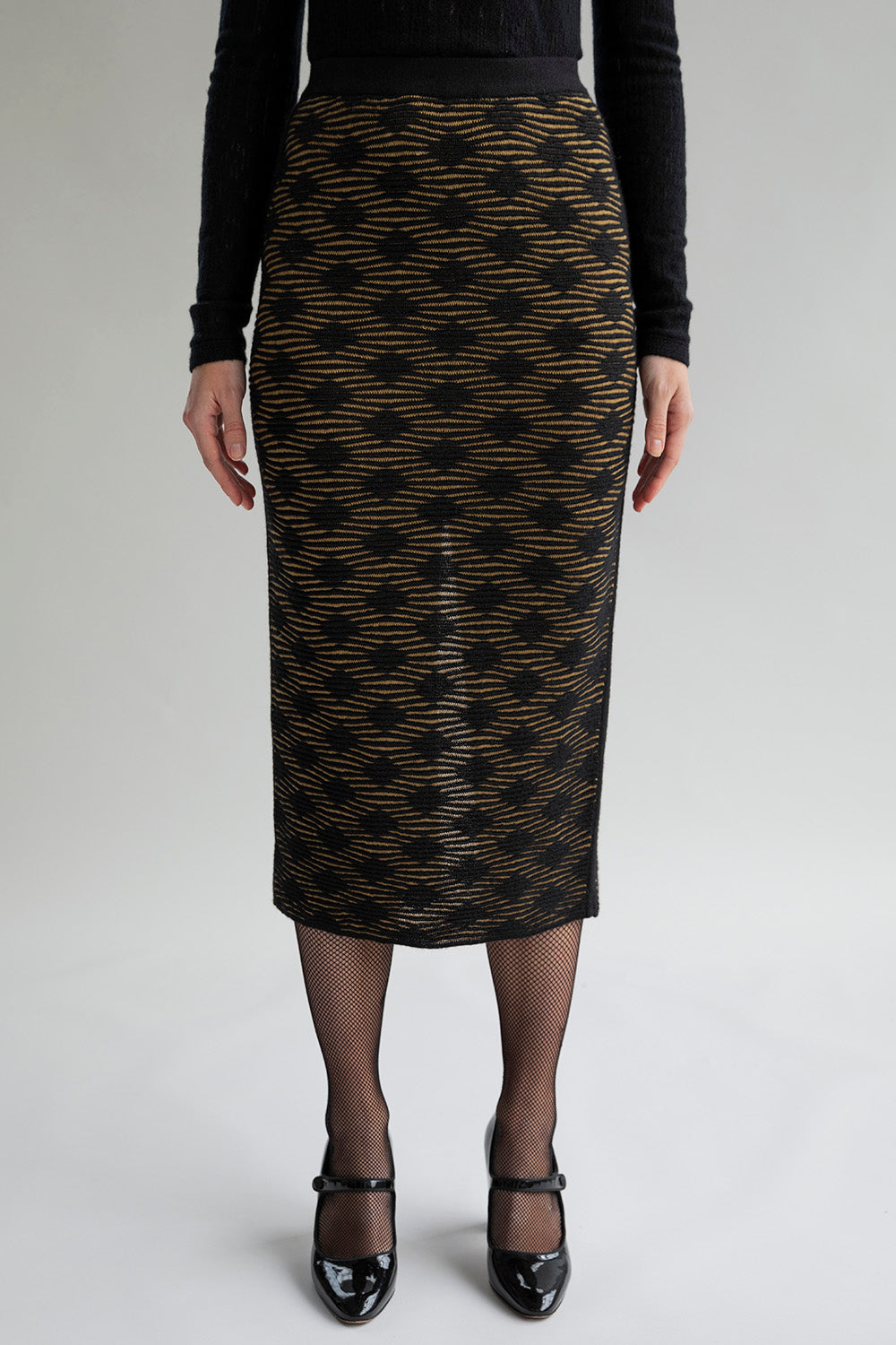 Golden black pencil skirt with a subtle monochromatic pattern, knitted from baby alpaca and cotton, worn by a model.