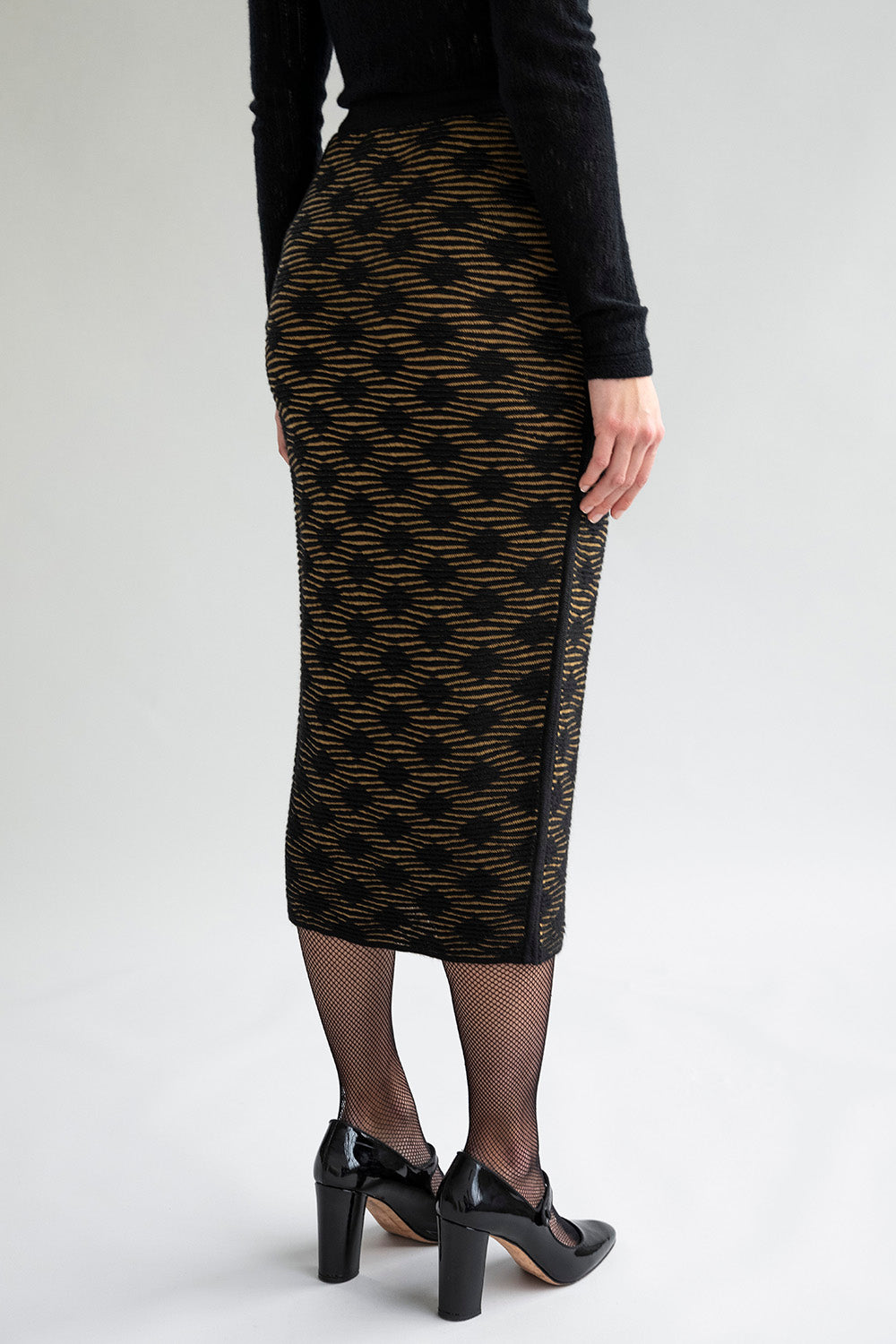 Side view of a slim-fitting golden black pencil skirt, featuring a subtle monochromatic pattern.