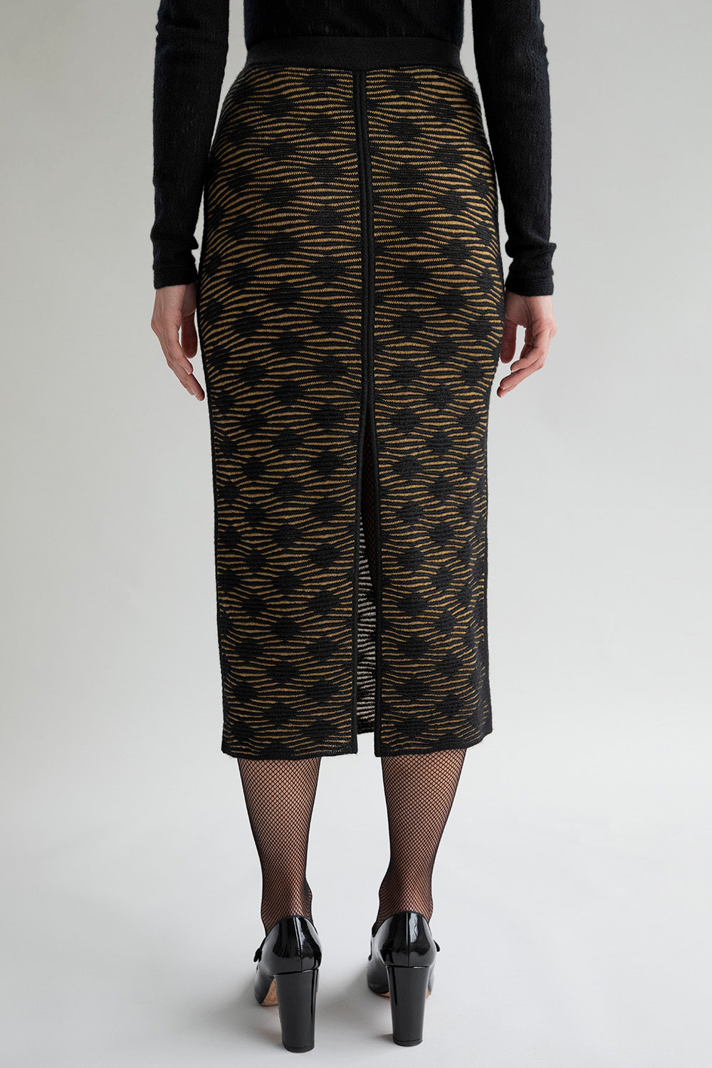 Back view of the golden black Ines pencil skirt, designed to be worn back to front, showing textured interest, an elegant slit, and a subtle pattern.