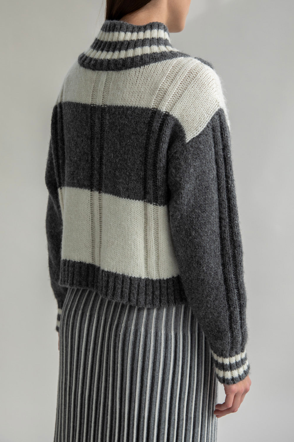 Side view of the Kari Plaid Pullover made from soft baby alpaca in grey and ivory. The pullover features a stylish plaid pattern and a comfortable fit.