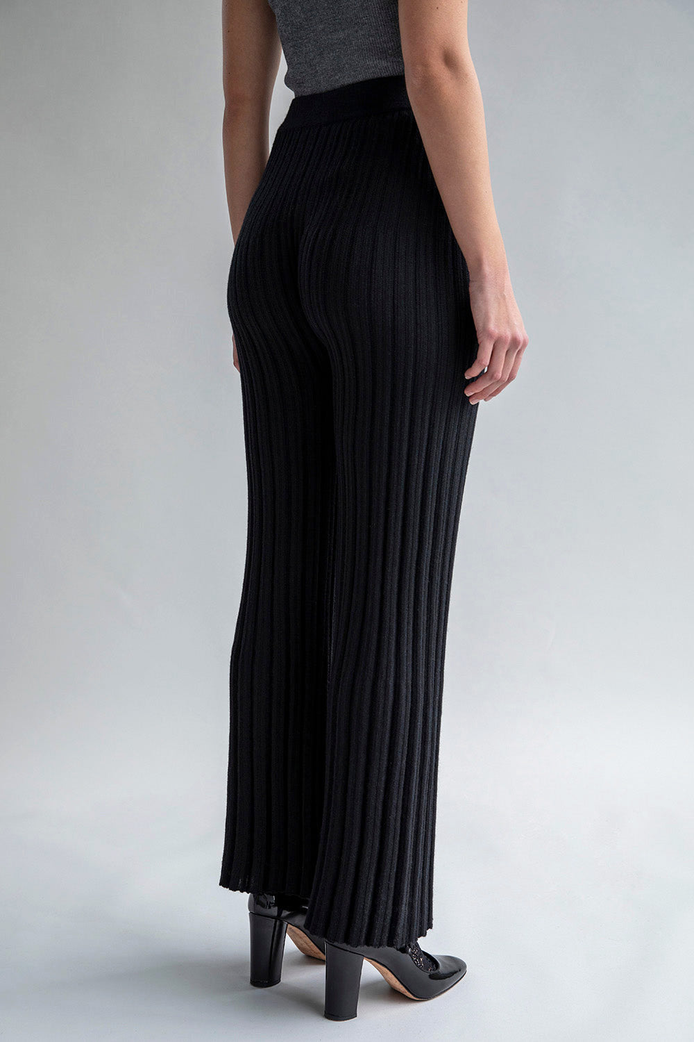 Side view of black trousers featuring a matte and shiny stripe pattern.