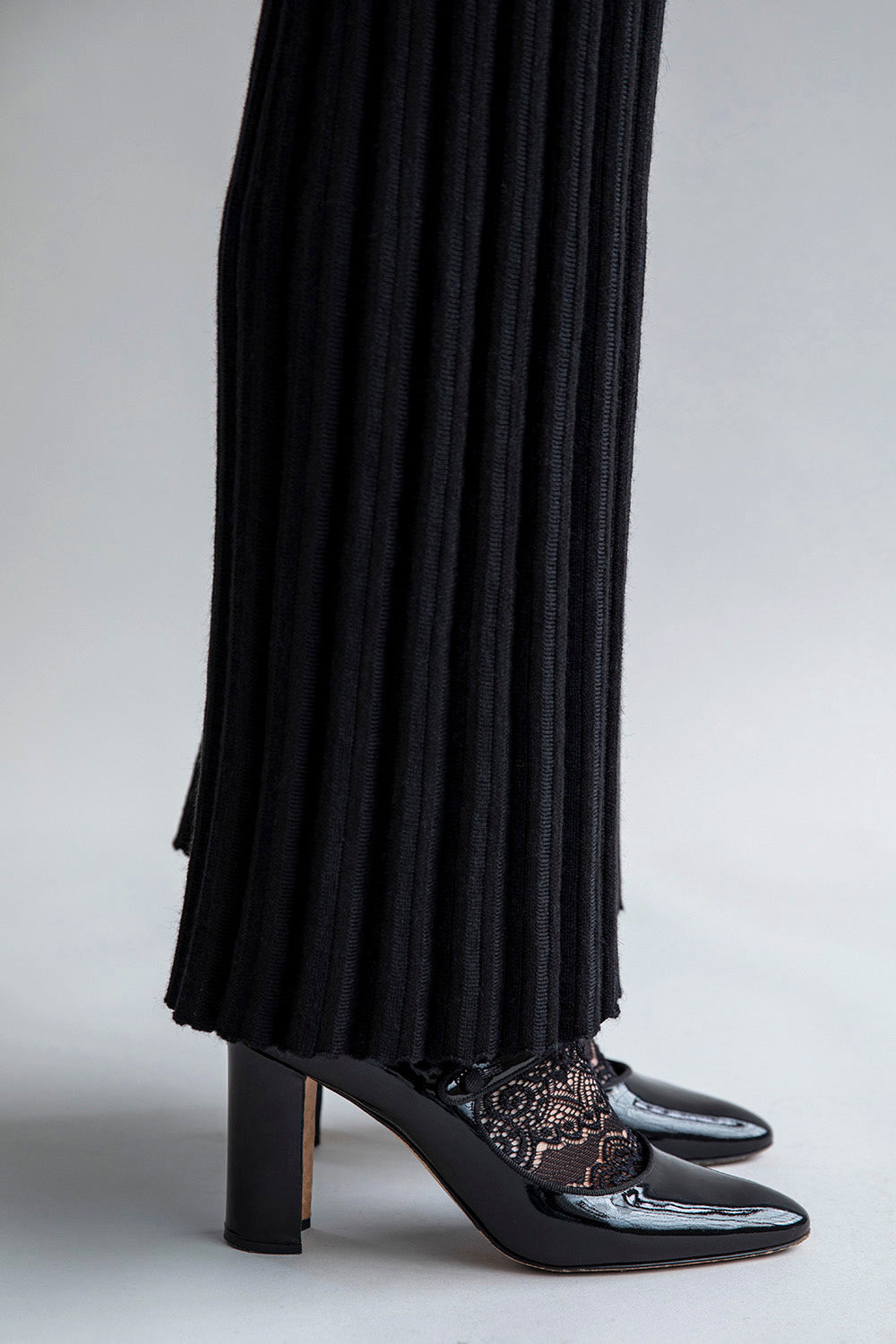 Side view of the pant leg in black displaying the flare-leg detail and pleated hem effect.