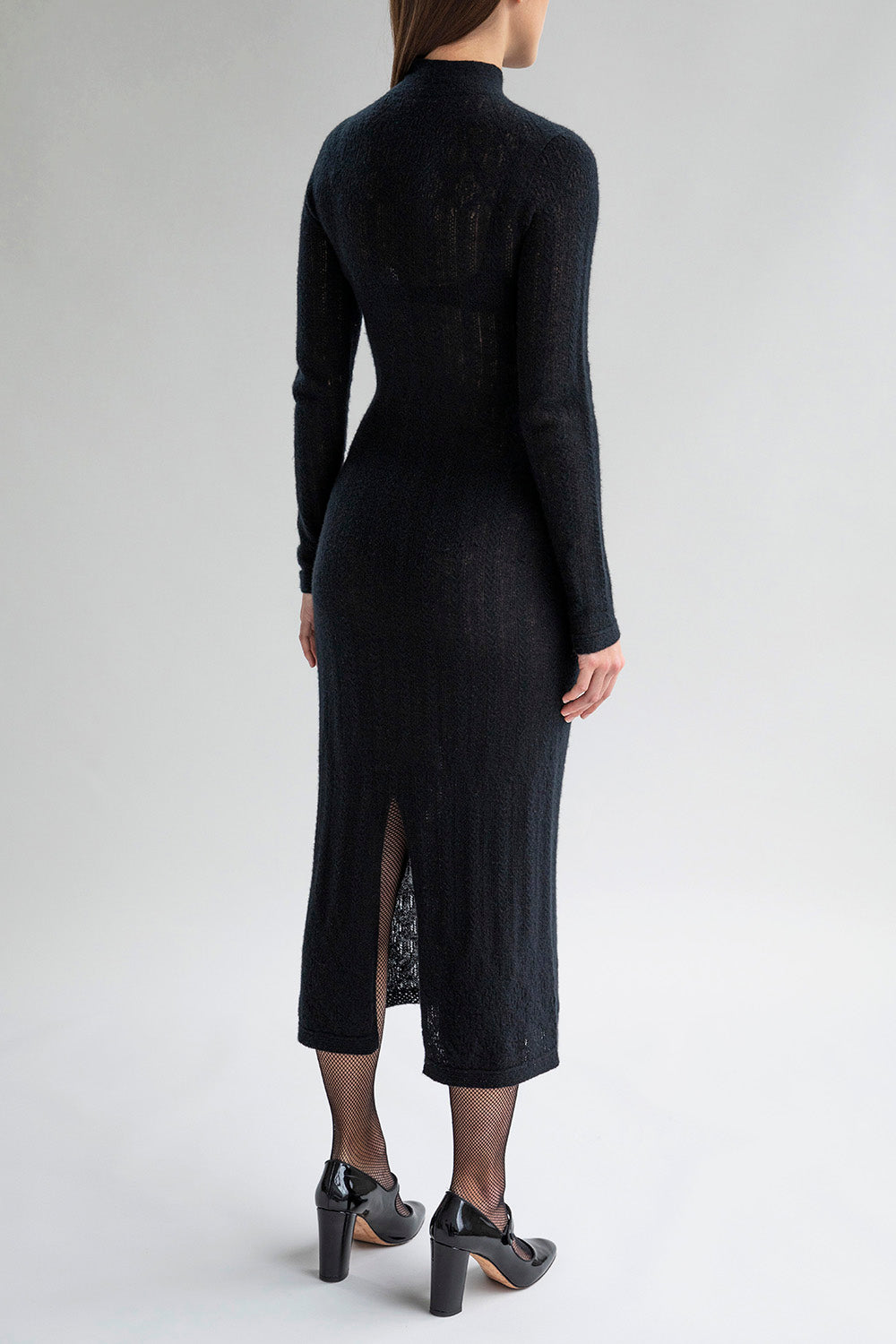 Back view of a woman wearing a lace pointelle dress with a mock neck and long sleeves.