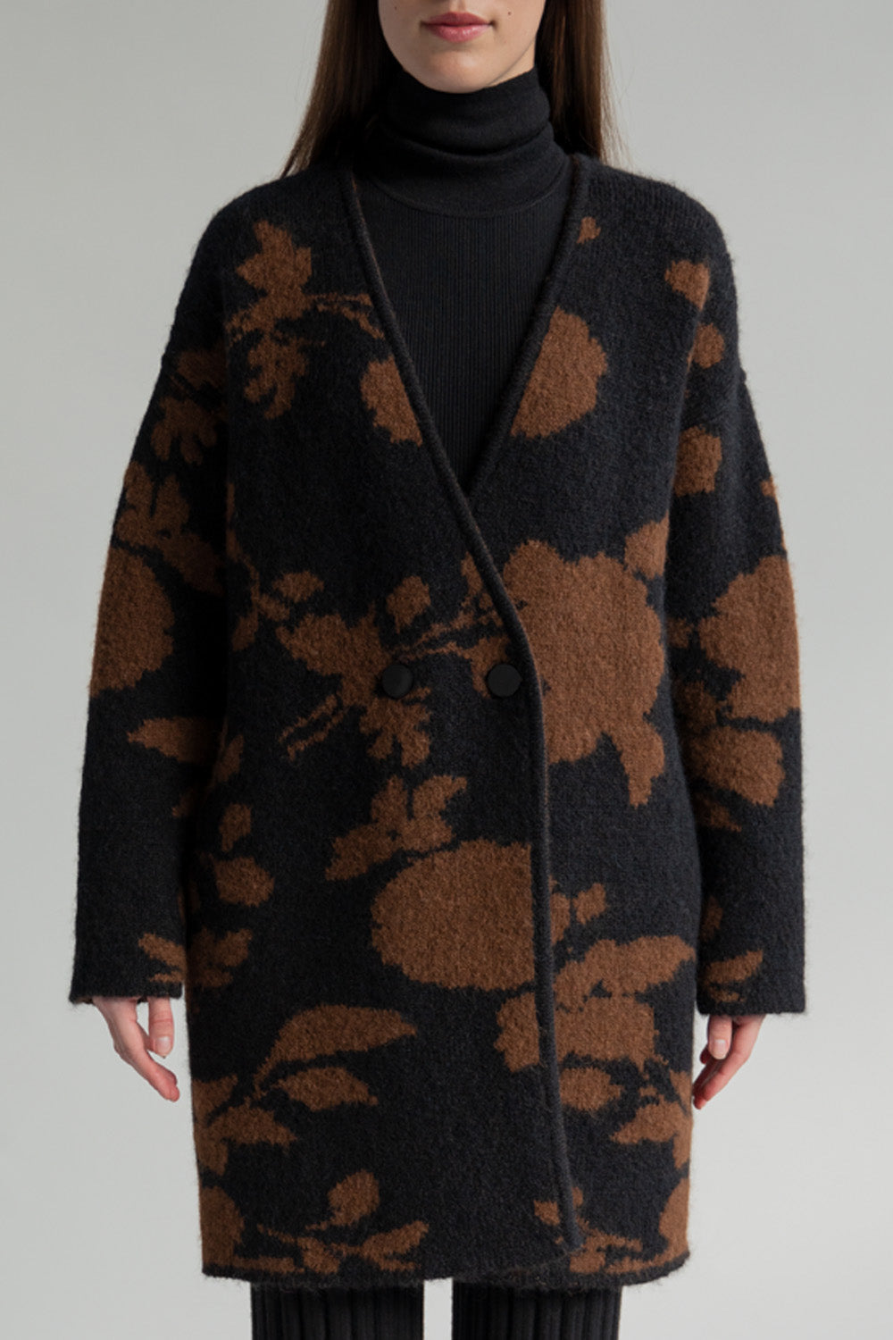 A model wearing a reversible coat with a floral print in black and camel colors, knitted in a double layer of alpaca blend yarn.