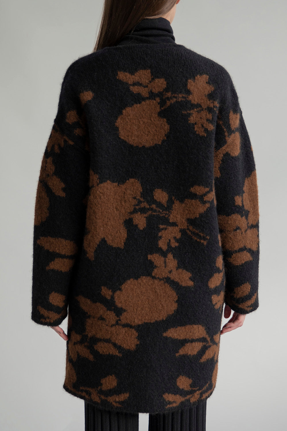 Full back view of a model wearing a reversible coat with a jacquard print in black and camel.