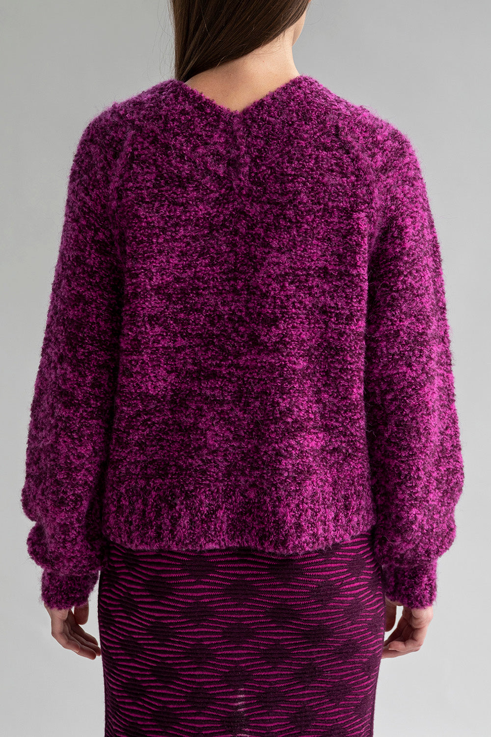 Full back view of a model wearing a fuchsia and aubergine alpaca-nylon blend sweater.