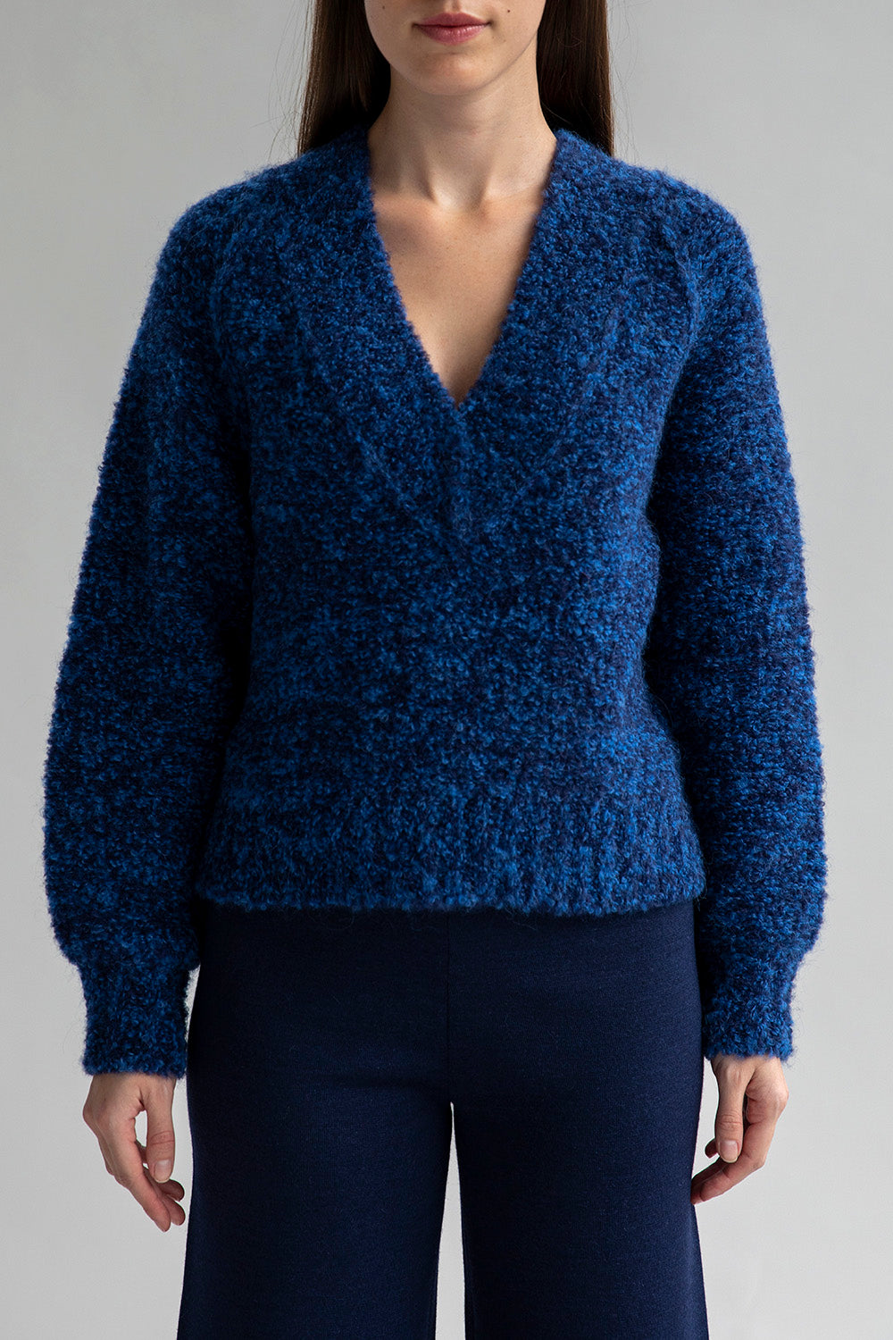 A woman wearing a Sky Navy bouclè V-Neck pullover sweater made from superfine alpaca.